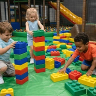 Trois enfants en train de jouer aux Légos géant dans une aire de jeux pour enfants