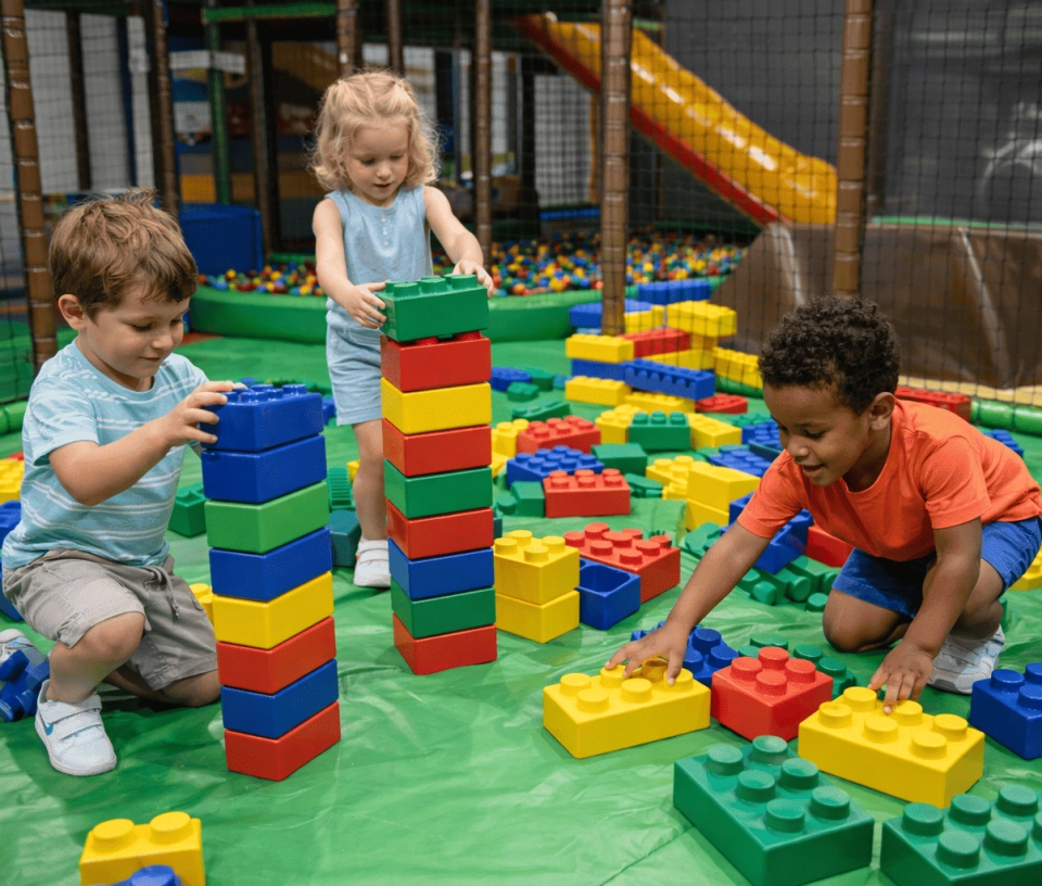 Trois enfants en train de jouer aux Légos géant dans une aire de jeux pour enfants