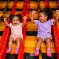 Deux enfants souriants descendant d'un toboggan dans une aire de jeux pour enfants