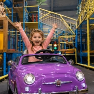 fille souriante voiture électrique parc de jeux interieur