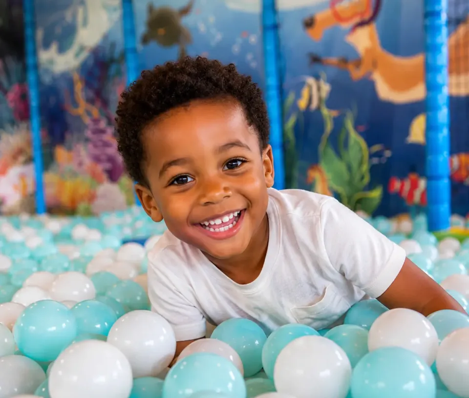 enfant souriant dans une piscine à balle