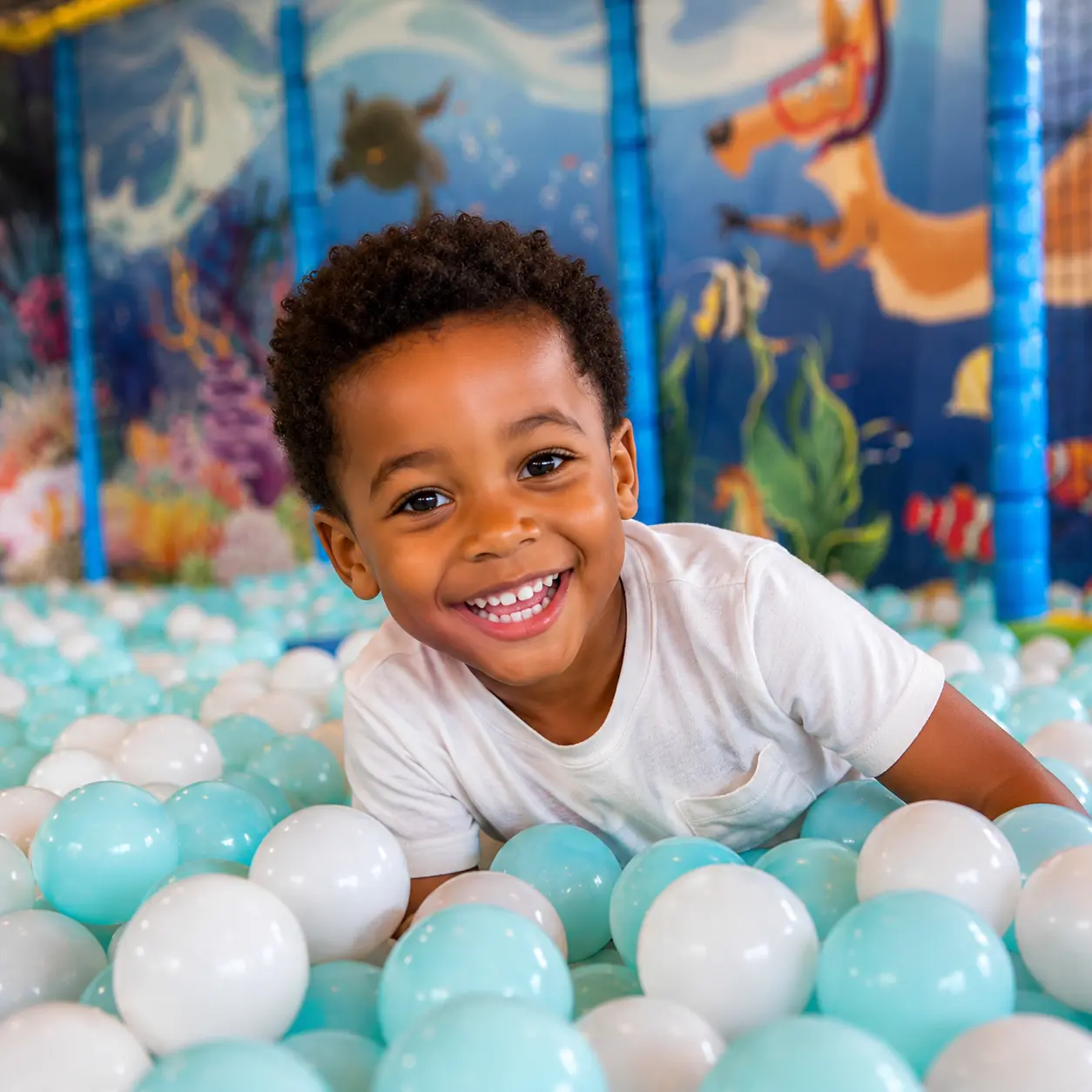 enfant souriant dans une piscine à balle